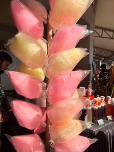 a bunch of pink and yellow candies in plastic bags on a table next to bottles