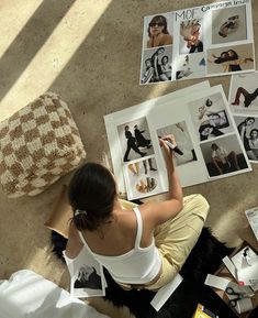 a woman is sitting on the floor working on her fashion design project, surrounded by photos and photographs