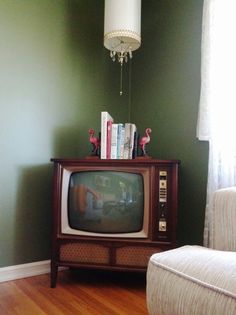 a small tv sitting on top of a wooden stand next to a white chair in a living room