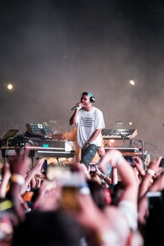 a man standing on top of a stage with his hands in the air while holding a microphone