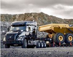 a large dump truck parked in front of a mountain