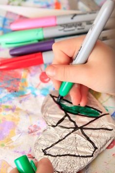 a child's hand writing on a piece of paper with crayons