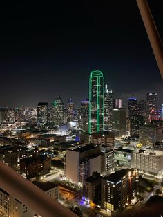 the city is lit up at night with green lights on it's skyscrapers