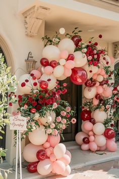 a bunch of balloons that are on the side of a building with flowers and greenery