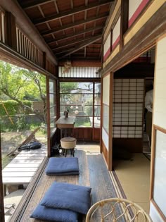 the inside of a japanese house with wood flooring and blue cushions on the ground