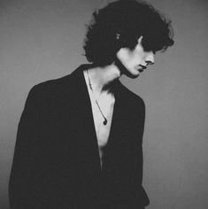 black and white photograph of a woman with dark hair wearing a suit, necklace and earrings