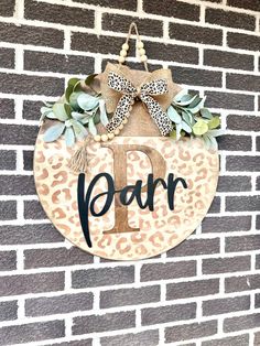 a leopard print door hanger on the side of a brick wall with a bow