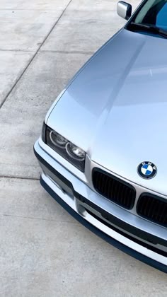 the front end of a silver car parked on concrete