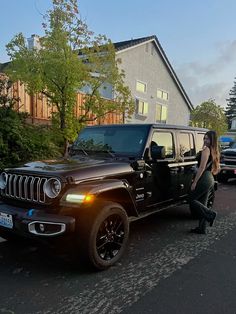 a woman sitting on the hood of a black jeep