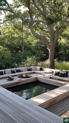 an outdoor living area with wooden decking and fire pit in the center, surrounded by trees
