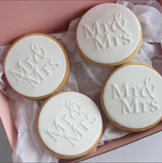 three decorated cookies in a pink box with white frosting on them and the words mr & mrs