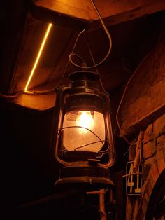 an old fashioned lantern hanging from the ceiling in a dark room with exposed beams and lights