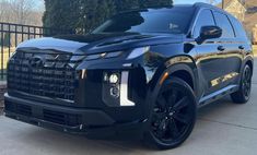 a black suv parked in front of a fence