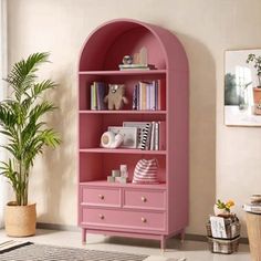 a pink bookcase with books and toys on it in the corner of a room