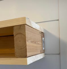 a piece of wood sitting on top of a wooden shelf next to a white wall