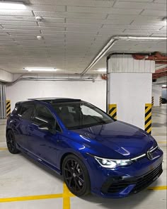 a blue car is parked in a parking garage with yellow and white stripes on the floor