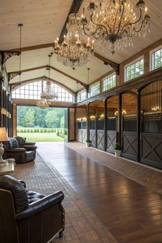 the inside of a horse barn with chandeliers hanging from the ceiling and windows