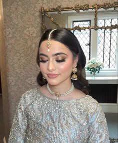 a woman in a silver outfit with pearls on her head and jewelry around her neck
