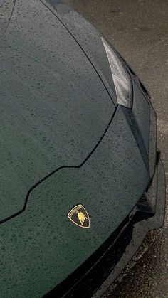 the front end of a green sports car covered in raindrops with a ferrari logo on it