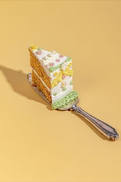 a piece of cake sitting on top of a spatula next to a yellow wall