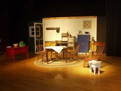 an empty stage with chairs and tables in the middle, on a wooden floor next to a wall