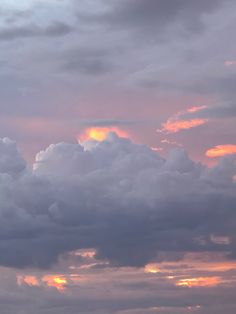 an airplane is flying in the sky with clouds above it at sunset or sunrise time