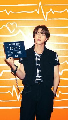 a young man holding up a sign in front of an orange background