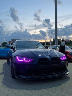 some cars parked in a parking lot with purple lights on the front and side of them