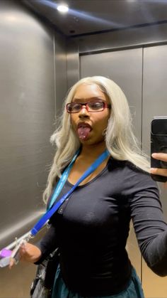 a woman taking a selfie in an elevator with her tongue out and holding a cell phone