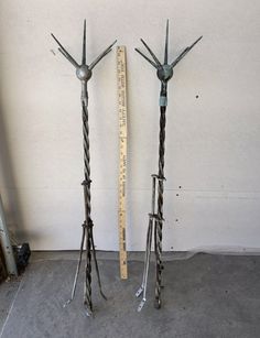 two metal birds are standing next to each other near a measuring tape on the floor