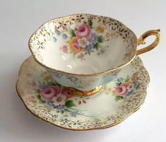 two cups and saucers with flowers on them sitting side by side in front of each other