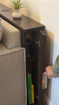 a person opening the door to a living room with a couch and bookshelf