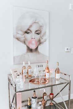 a table with bottles and glasses on top of it, next to a painting that reads proofbar carts don't have to be ridiculously