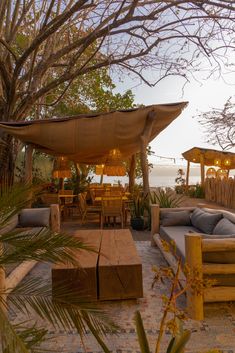 an outdoor living area with couches, tables and umbrellas