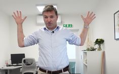 a man standing in an office with his hands up