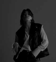 black and white photograph of a woman with her hands in the air while wearing a leather vest