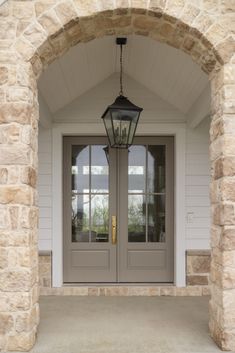 a light hanging from the side of a door in front of a stone building with two windows