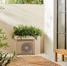 an air conditioner sitting on top of a wooden floor next to a plant pot