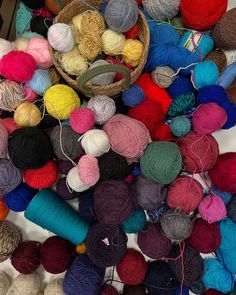 many balls of yarn are piled on top of each other in different colors and sizes