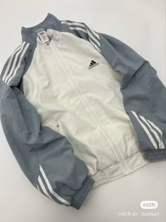 Blue with white streaks going down on the sleeves, adidas black logo on the right side of chest, rest is crème white Color no extra details