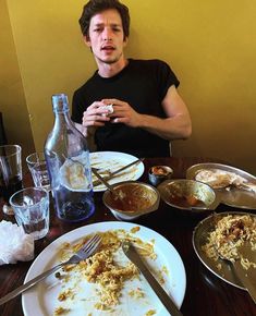 a man sitting at a table full of food and empty plates in front of him
