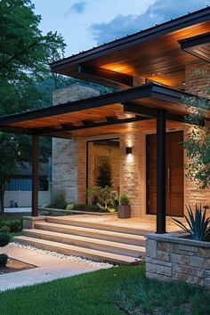 a modern house with steps leading to the front door and covered patio area at night