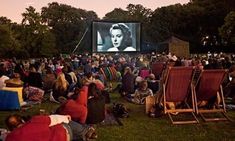 an outdoor movie theater with people sitting in lawn chairs and watching the movies on screen