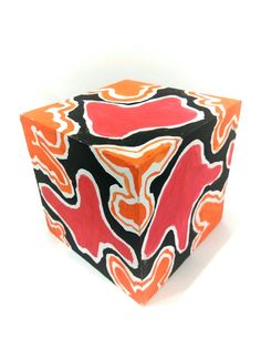 an orange and black cube with red designs on the sides, sitting in front of a white background