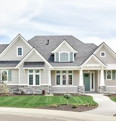 a large gray house with white trim on the front and side windows, grass in front