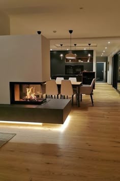 a living room filled with furniture and a fire place next to a dining table on top of a hard wood floor