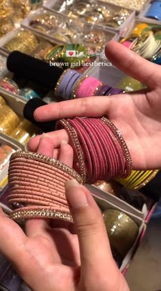 two hands holding bracelets in front of jewelry