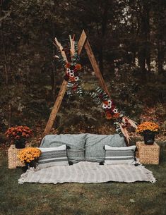 an outdoor seating area with pillows, blankets and flowers on the grass in front of trees