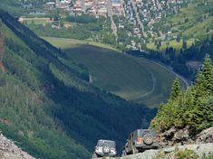 two jeeps are parked on the side of a mountain overlooking a town and valley