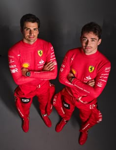 two men in red racing suits are posing for a photo with their hands on their hipss